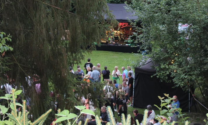 Blick zwischen den Bäumen auf die Bühne beim 1. „Rock am Teich“