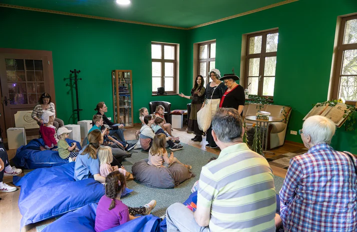 Menschen sitzen in der "Magischen Bibliothek" und hören einer Veranstaltung zu.  