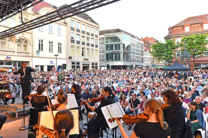 Bühne mit den Musikerinnen und Musiker des Göttinger Symphonieorchesters. Dicht gedrängt davor die Zuschauerinnen auf dem Marktplatz.