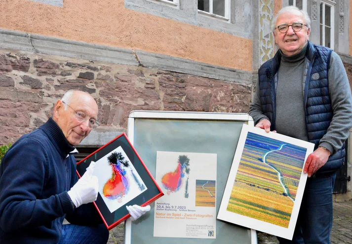 zwei Fotografen zeigen Ausstellungsplakat