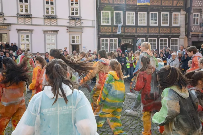 Kinder in bunt bemalten Anzügen tanzen auf dem Kirchplatz