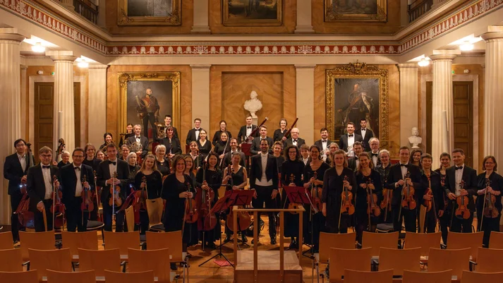 Orchester stehend in schwarz gekleidet mit Instrumenten