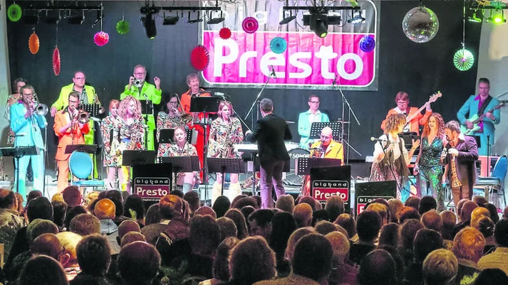 Bandfoto der Bigband Presto, in quietschbunten Kostümen, erstellt im Bühnenbereich 