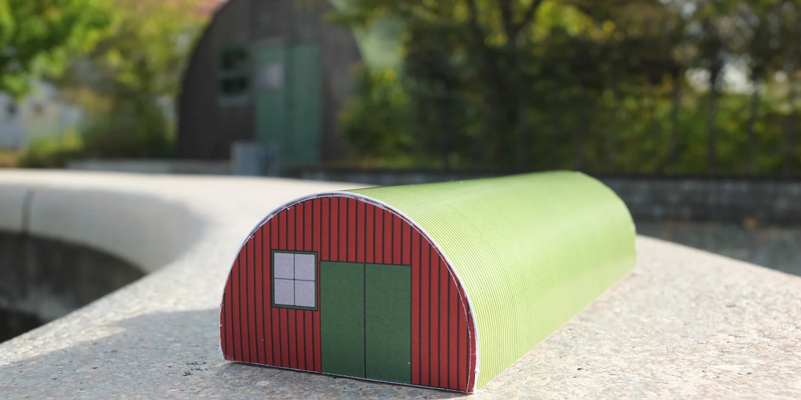 grüner Bastelbogen der Nissenhütte vor der originalen Hütte