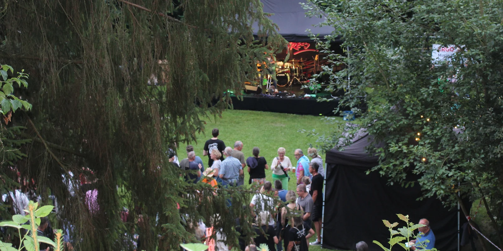 Blick zwischen den Bäumen auf die Bühne beim 1. „Rock am Teich“