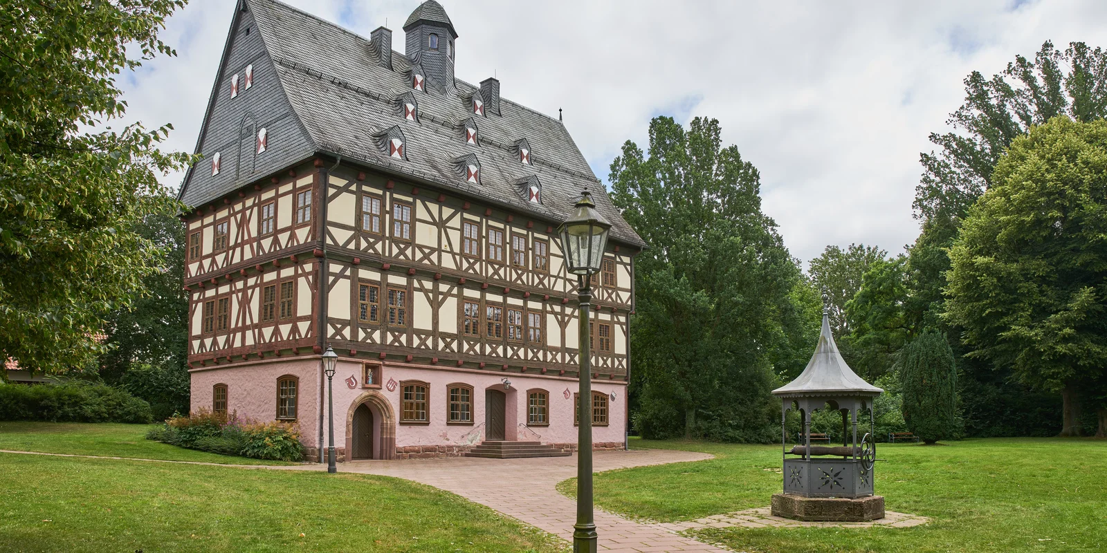 Außenaufnahme des Schloss Giebolderhausen. Ein Fachwerkbau mit gemauertem rosa Erdgeschoss.