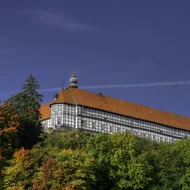 Blick auf Schloss Herzberg, ein langer Fachwerkbau mit rotem Dach und kleinem Türmchen
