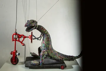 Eine Dinosauriermarionette auf einem Tretroller