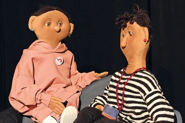 Zwei Puppen sitzen auf einem Sofa