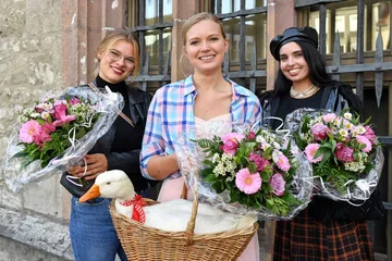 Drei Frauen mit Blumen und eine Gans im Korb