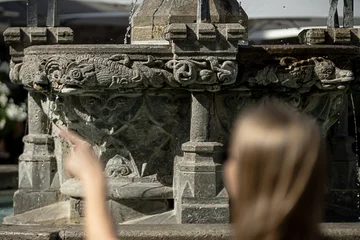 Im Vordergrund (unscharf) junge Frau zeigt auf Gänselieselbrunnen