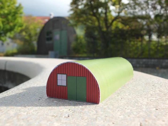 grüner Bastelbogen der Nissenhütte vor der originalen Hütte