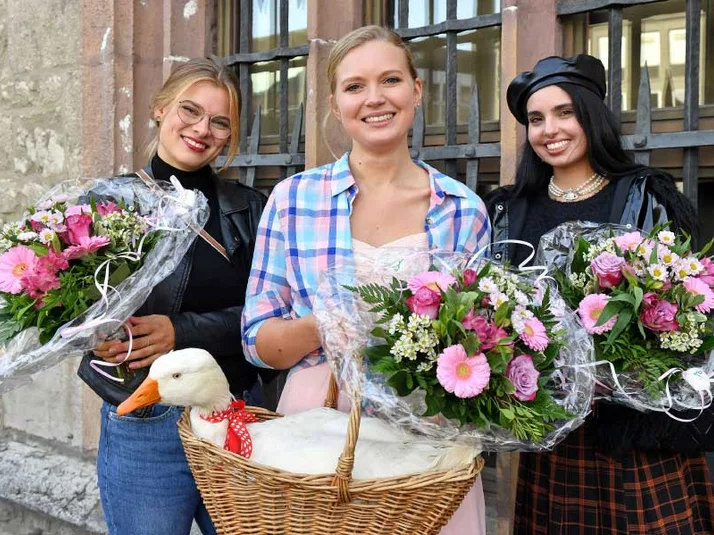 Drei Frauen mit Blumen und eine Gans im Korb