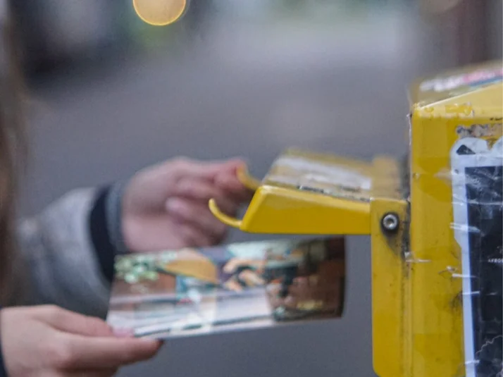 jemand wirft eine Postkarte in einen Briefkasten