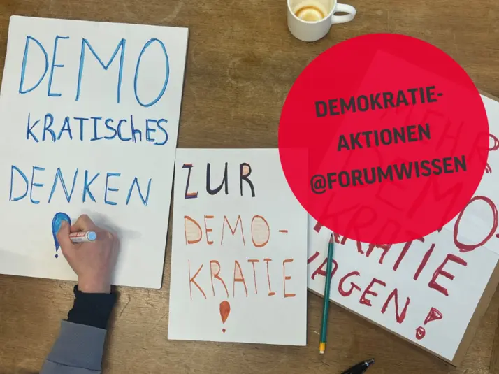 Eine Kinderhand malt an einem Demoplakat auf einem Tisch.