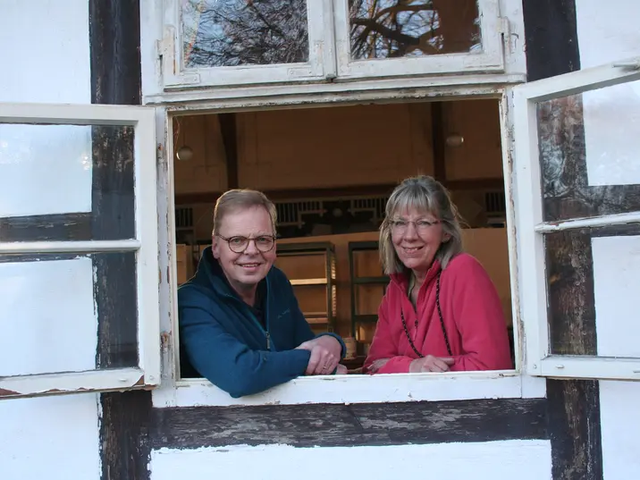 Ralf und Ute Lesjak schauen aus dem geöffneten Fenster eines Fachwerkhauses